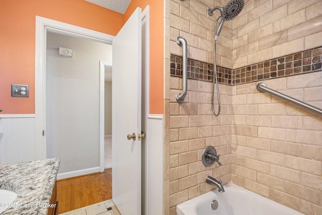 full bath with wainscoting, vanity, bathtub / shower combination, and wood finished floors