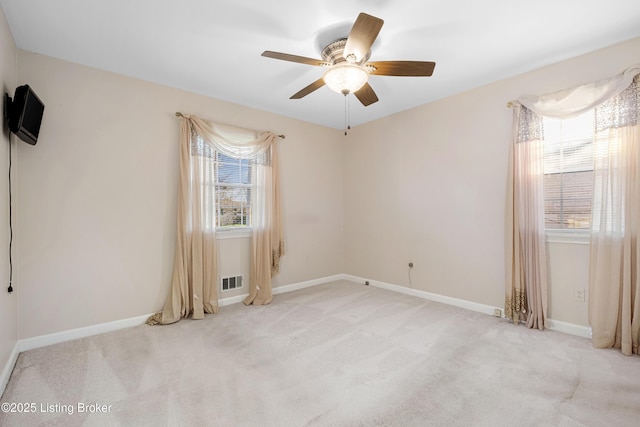 empty room with plenty of natural light, a ceiling fan, baseboards, and light colored carpet