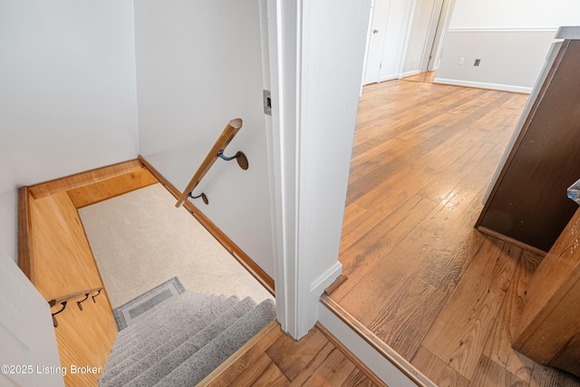 stairway featuring baseboards, wood-type flooring, and visible vents