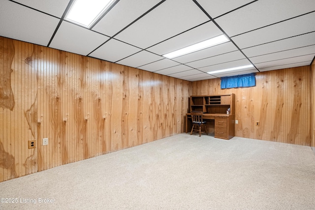 interior space with carpet floors, wood walls, and a paneled ceiling