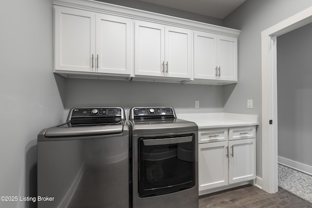 clothes washing area featuring washing machine and dryer, cabinet space, baseboards, and dark wood finished floors