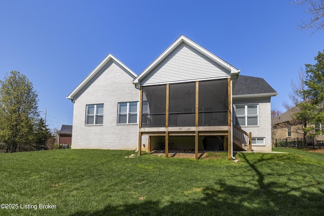 rear view of property with a sunroom, brick siding, and a lawn