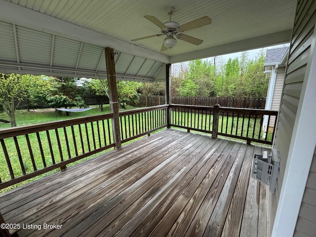 wooden terrace featuring a lawn, a ceiling fan, and a fenced backyard