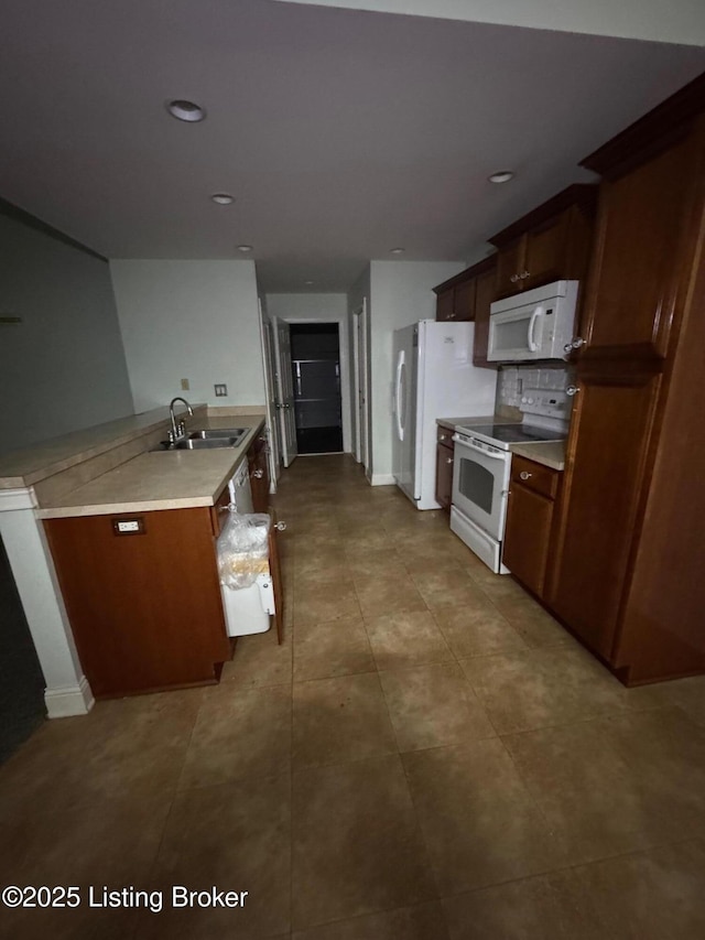 kitchen with a sink, light countertops, tile patterned floors, and white appliances