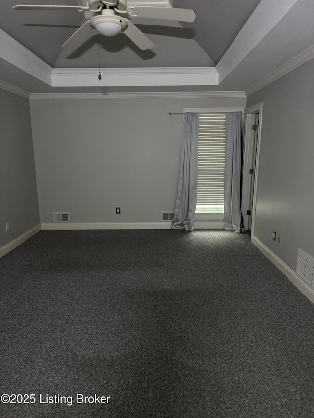 carpeted empty room with visible vents, ornamental molding, and a raised ceiling