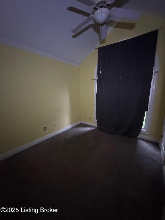 spare room with baseboards, ceiling fan, dark carpet, and lofted ceiling