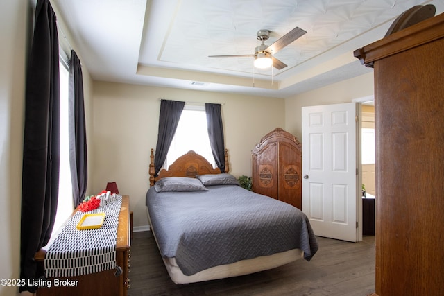 bedroom with wood finished floors, a raised ceiling, and ceiling fan
