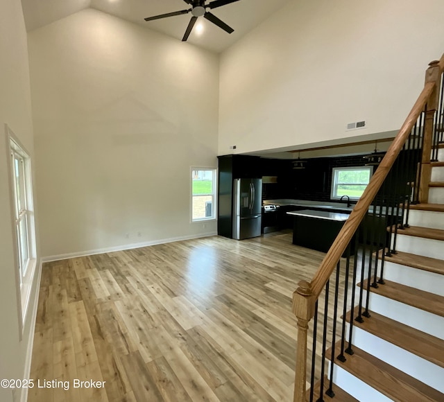 383 Webb Ln, Bedford, KY 40006 - unfurnished living room with high vaulted ceiling, ceiling fan, stairway, light wood-style flooring, and baseboards
