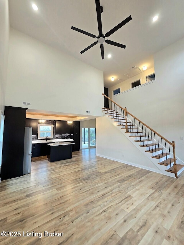 383 Webb Ln, Bedford, KY 40006 - unfurnished living room featuring a towering ceiling, stairway, ceiling fan, light wood-style flooring, and recessed lighting