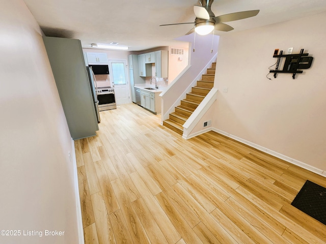 611 Malcolm Ave, Louisville, KY 40223 - unfurnished living room featuring a ceiling fan, light wood-style floors, and stairs