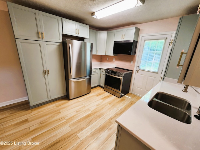 611 Malcolm Ave, Louisville, KY 40223 - kitchen with stainless steel appliances, a textured ceiling, light wood-type flooring, light countertops, and tasteful backsplash