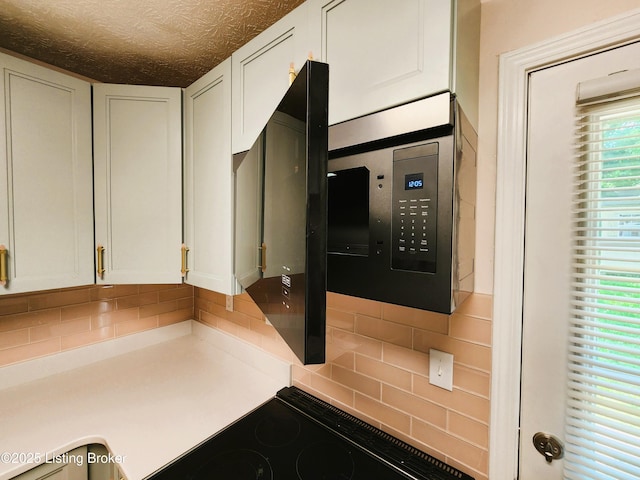 611 Malcolm Ave, Louisville, KY 40223 - kitchen featuring decorative backsplash, white cabinets, light countertops, range, and a textured ceiling