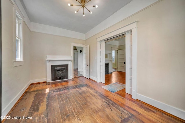 2060 S Preston St, Louisville, KY 40217 - unfurnished living room featuring a fireplace, wood-type flooring, baseboards, and a chandelier
