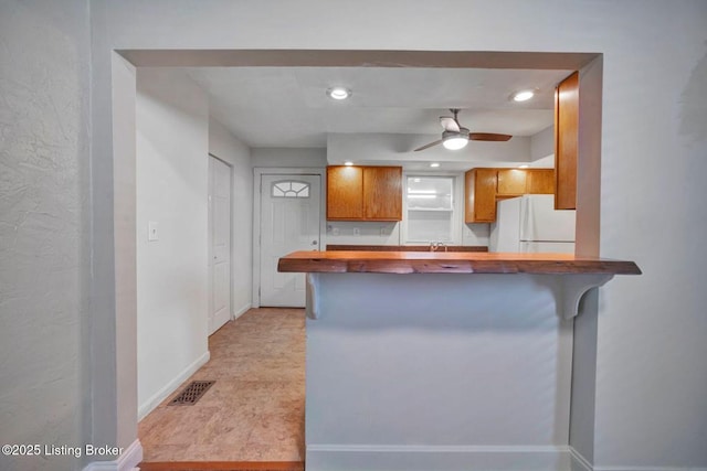 2060 S Preston St, Louisville, KY 40217 - kitchen featuring freestanding refrigerator, ceiling fan, brown cabinetry, butcher block countertops, and a breakfast bar area