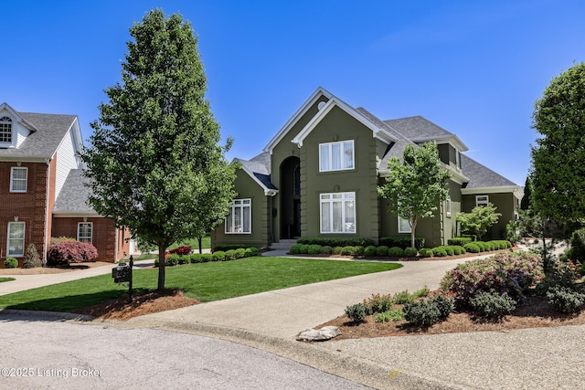 traditional-style house featuring a front yard and a shingled roof