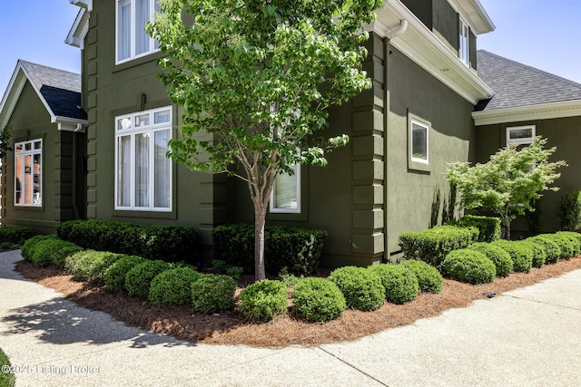 view of side of home featuring stucco siding and roof with shingles