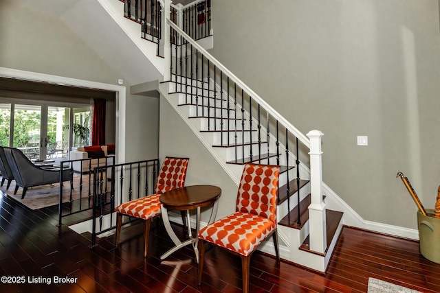 stairs with baseboards, a towering ceiling, and wood finished floors