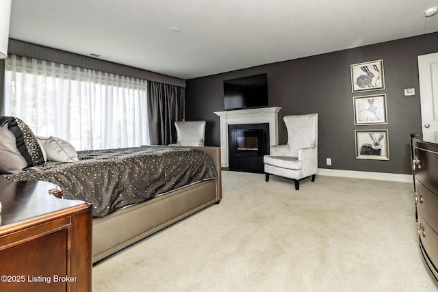 carpeted bedroom featuring visible vents, baseboards, and a glass covered fireplace