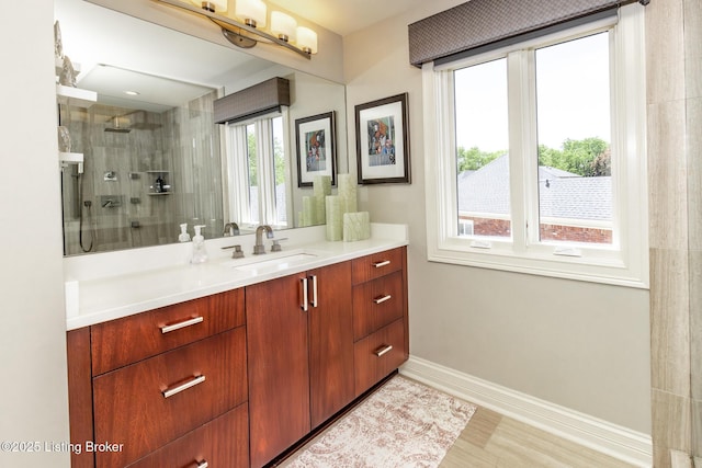 bathroom with vanity, baseboards, and tiled shower
