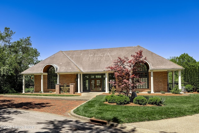 ranch-style home with a front yard, brick siding, and french doors