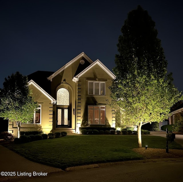 traditional-style house with a yard and stucco siding