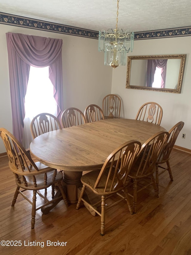 dining room with wood-type flooring, a notable chandelier, baseboards, and plenty of natural light