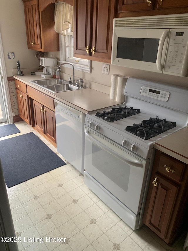 kitchen with light countertops, light floors, a sink, and white appliances