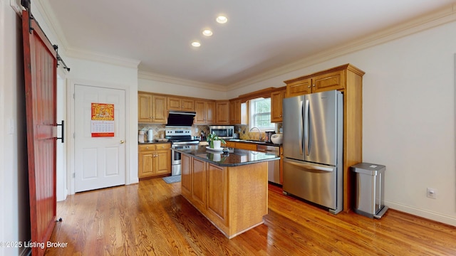 10513 Mountain Ash Ln, Prospect, KY 40059 - kitchen with appliances with stainless steel finishes, a barn door, light wood finished floors, a kitchen island, and ornamental molding