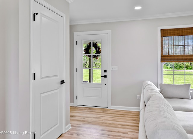doorway to outside featuring baseboards, ornamental molding, plenty of natural light, and light wood-style floors