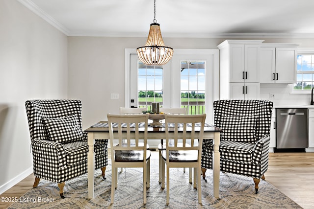 dining space featuring crown molding, light wood-type flooring, and a notable chandelier