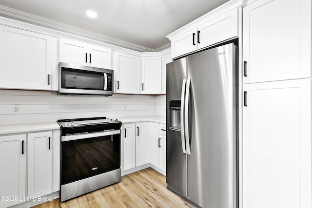 kitchen with light wood-style flooring, light countertops, white cabinets, and appliances with stainless steel finishes