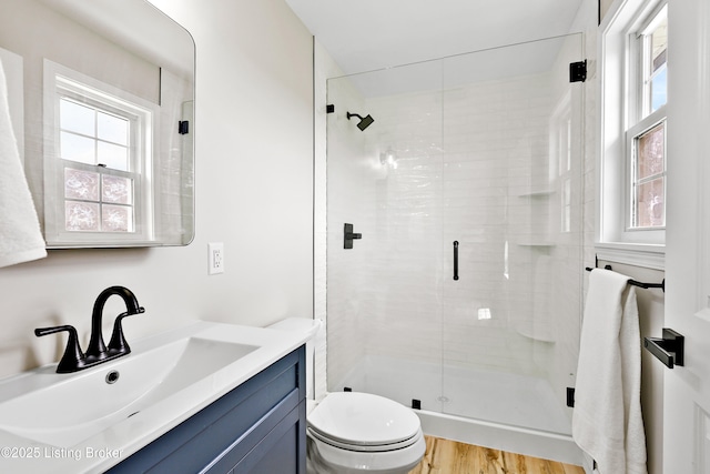 bathroom featuring a stall shower, toilet, and plenty of natural light