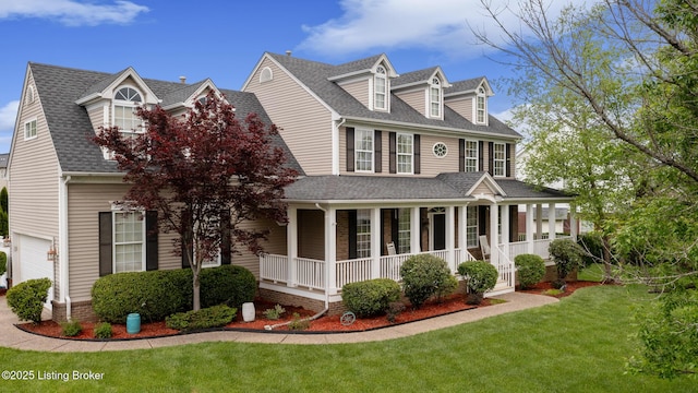 view of front of house featuring a front yard, a porch, a shingled roof, and a garage