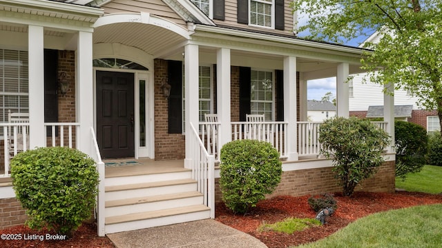 property entrance featuring a porch and brick siding