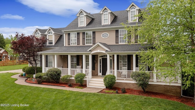 view of front of property featuring a porch, roof with shingles, and a front yard