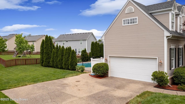 view of side of home featuring concrete driveway, a yard, a garage, and fence