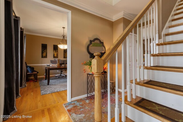 stairway with baseboards, crown molding, and wood finished floors