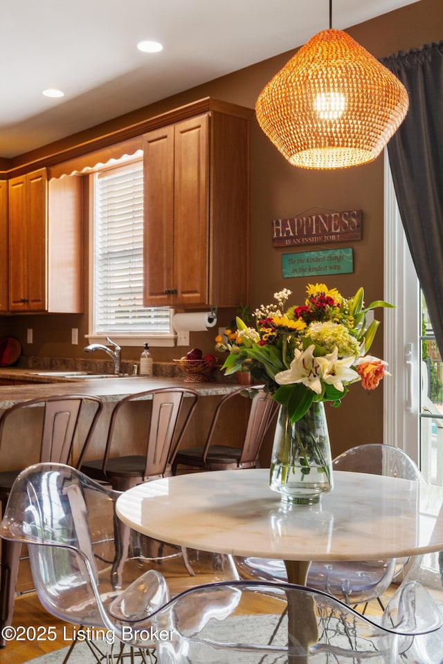 kitchen featuring a sink, a chandelier, brown cabinetry, and a healthy amount of sunlight