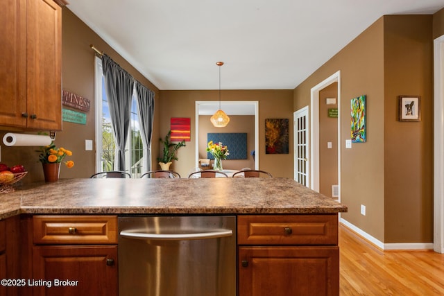 kitchen with stainless steel dishwasher, decorative light fixtures, brown cabinetry, a peninsula, and light wood-style floors