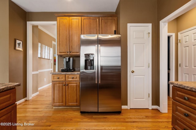 kitchen featuring stainless steel fridge with ice dispenser, light wood-type flooring, and brown cabinets