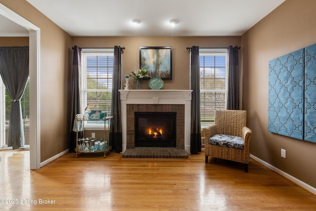 living area featuring a healthy amount of sunlight, a fireplace, and wood finished floors