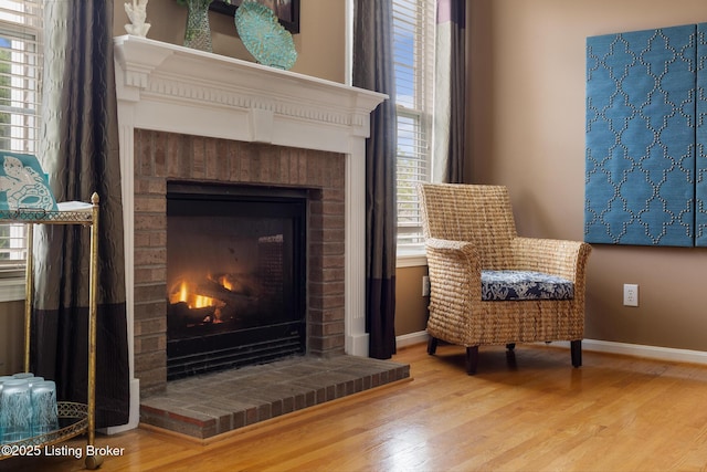 living area with baseboards, a fireplace, and wood finished floors
