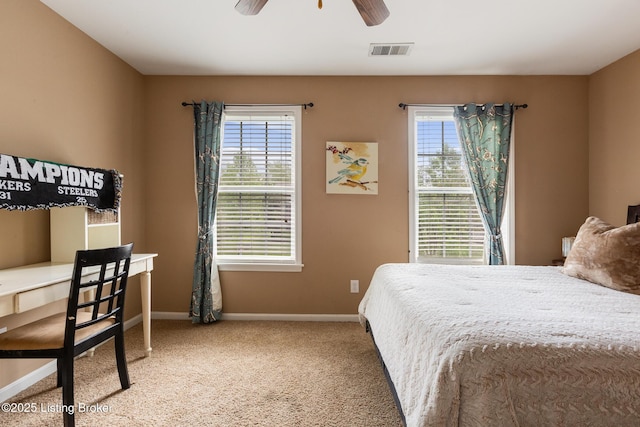 carpeted bedroom featuring multiple windows, visible vents, baseboards, and ceiling fan