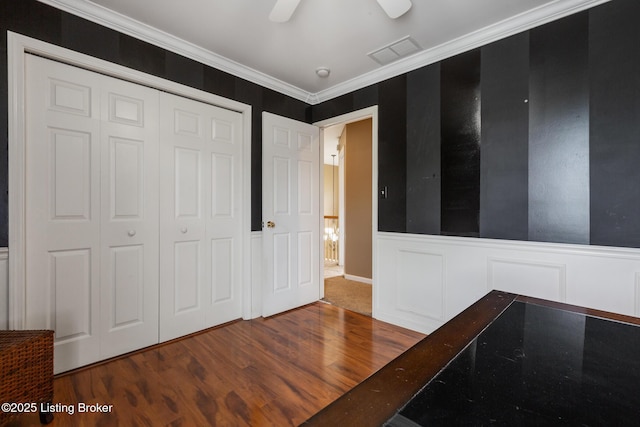 interior space featuring crown molding, a closet, visible vents, and wood finished floors