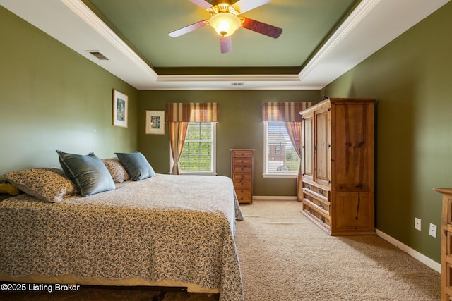 bedroom with a ceiling fan, a tray ceiling, baseboards, visible vents, and light colored carpet