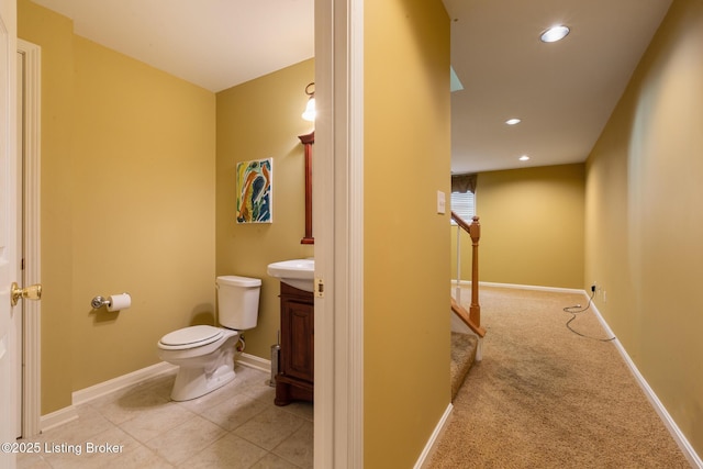 bathroom with toilet, baseboards, vanity, and recessed lighting