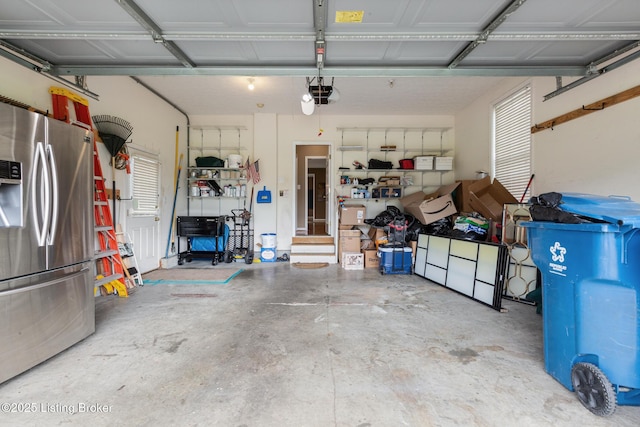 garage featuring stainless steel refrigerator with ice dispenser and a garage door opener