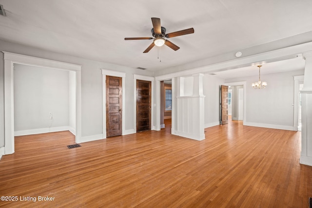 unfurnished living room featuring baseboards, light wood-style floors, visible vents, and ceiling fan with notable chandelier