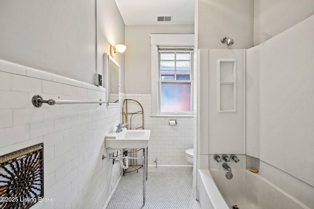 full bathroom featuring tile walls, toilet, wainscoting, visible vents, and tile patterned floors
