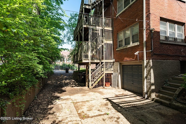view of home's exterior featuring an attached garage, brick siding, stairway, and driveway